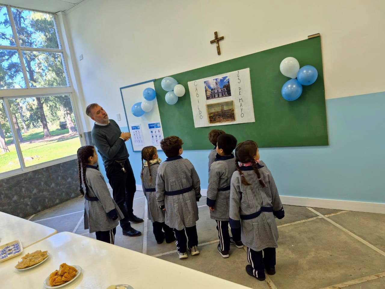Acto del 25 de Mayo: el maestro con los chicos frente al pizarrón del Cabildo