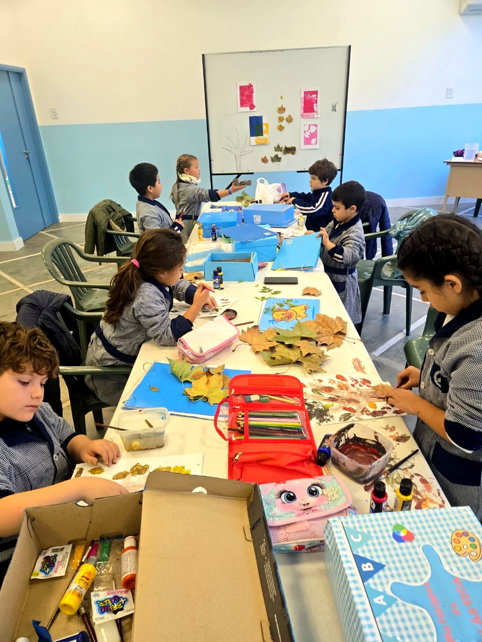 Chicos en clase de plástica con hojas de otoño y témperas